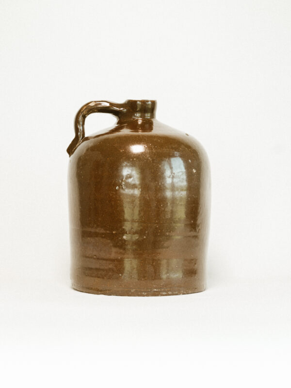 brown ceramic jug with handle against white background
