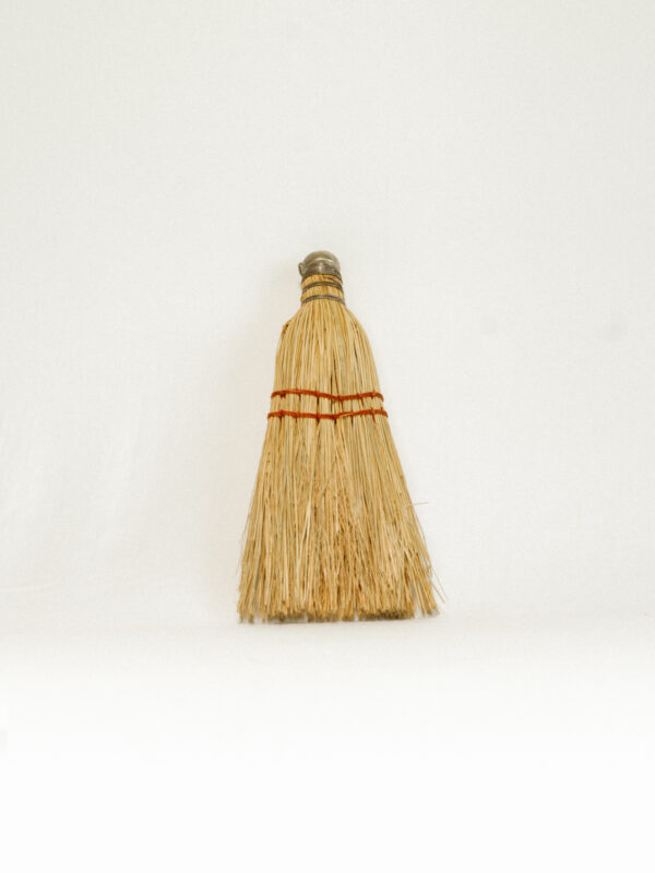 small handheld broom against white background