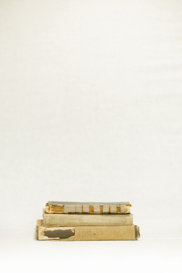 stack of vintage, tattered books against white background