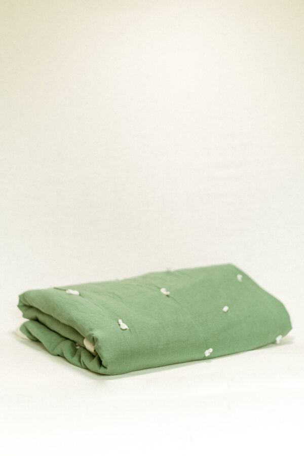 vintage green quilt, folded and set against a white background
