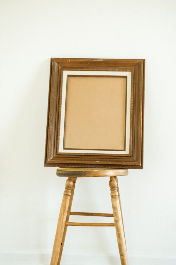 wooden picture frame leaning against wooden stool