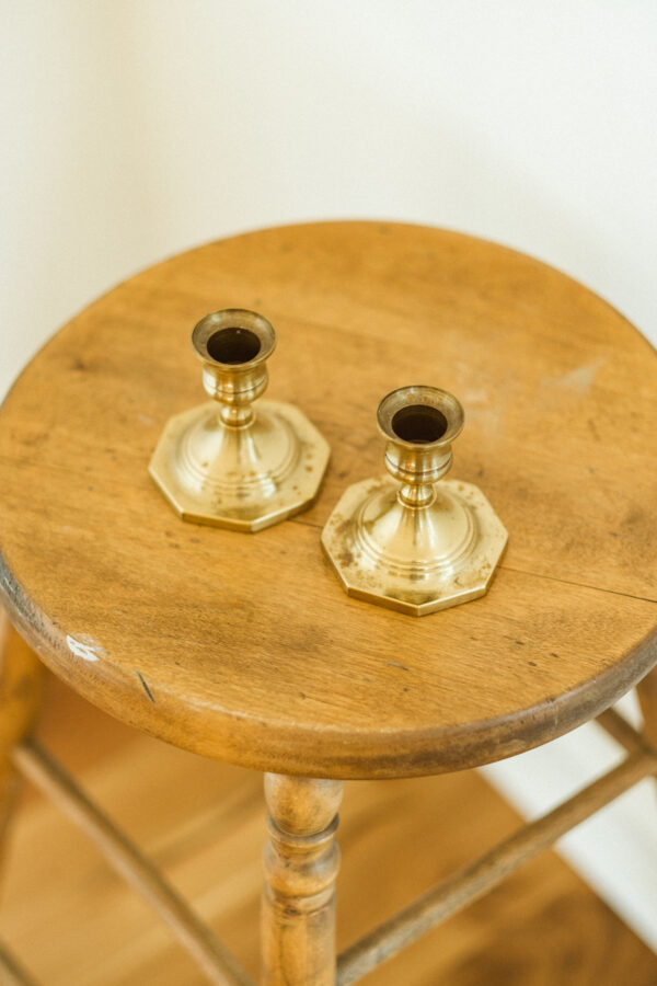 brass candlestick holders sitting on antique stool